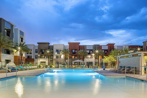 a swimming pool with palm trees and apartments in the background