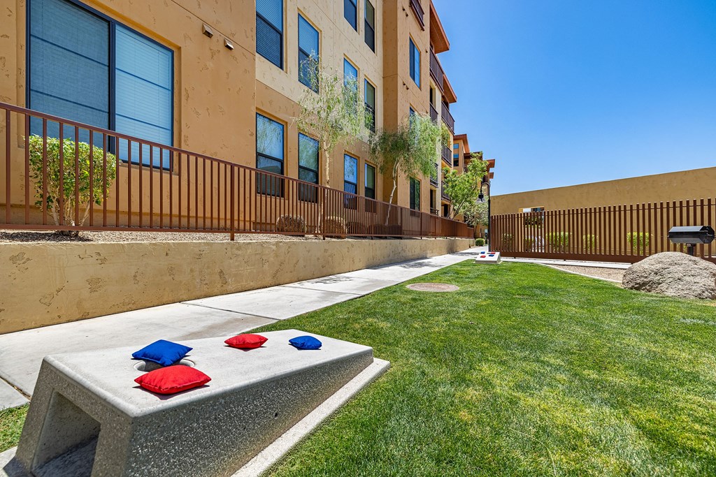 a yard with a stone table with red and blue pillows on it