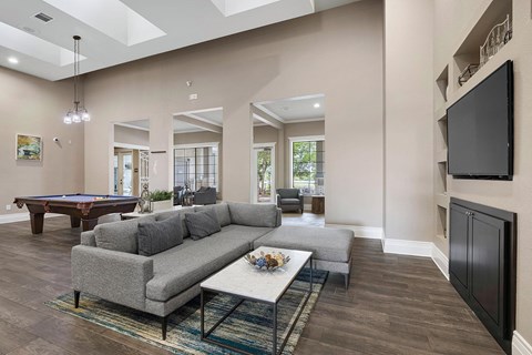A living room with a grey couch and a pool table.