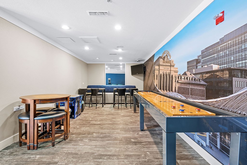 a games room with a shuffleboard table and tables and chairs