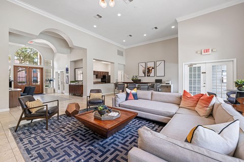 A living room with a blue rug and a grey couch.