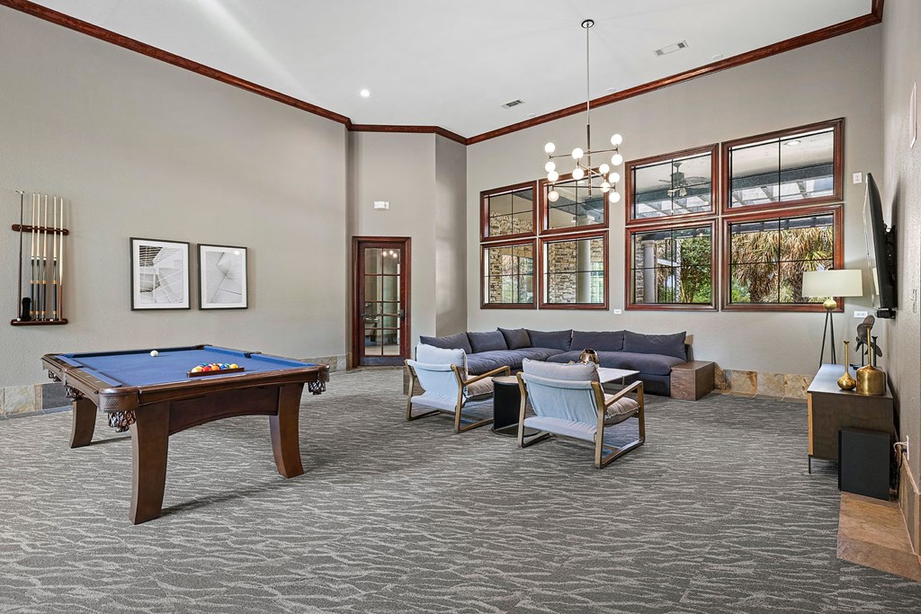 A billiard table is in the middle of a room with a couch and chairs.