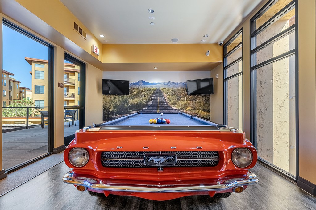 a pool table in a house with a red car in the middle