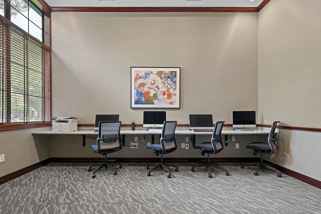 A room with a large table and chairs with a painting on the wall.