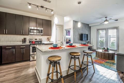 A kitchen with a white countertop and wooden bar stools.