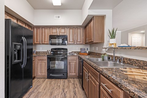 A kitchen with a black refrigerator and wooden cabinets.