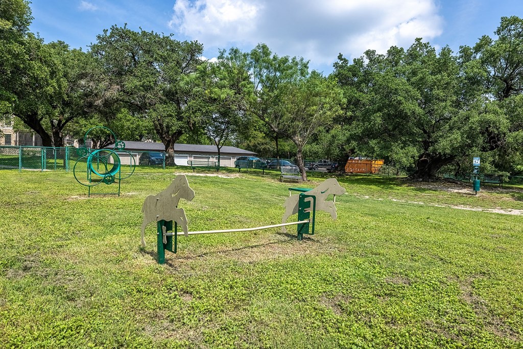 A park with a horse-shaped swing set and a green bench.