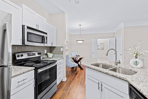 A kitchen with white cabinets and a black countertop.