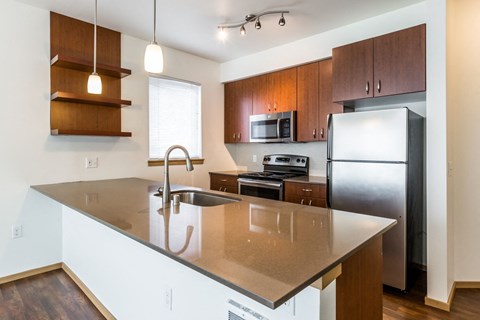 A kitchen with a refrigerator, microwave, and oven.