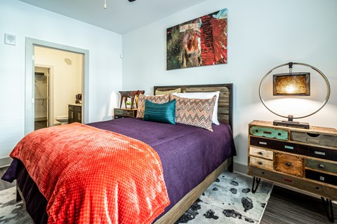 A bedroom with a bed, a dresser, and a painting on the wall.