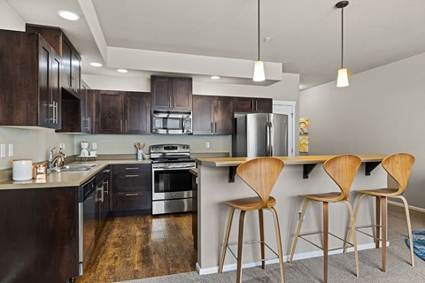 A modern kitchen with dark wood cabinets and a stainless steel refrigerator.