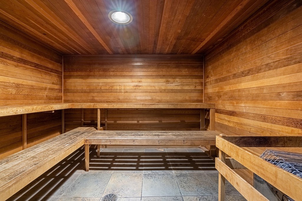 A wooden sauna with benches and a light on the ceiling.