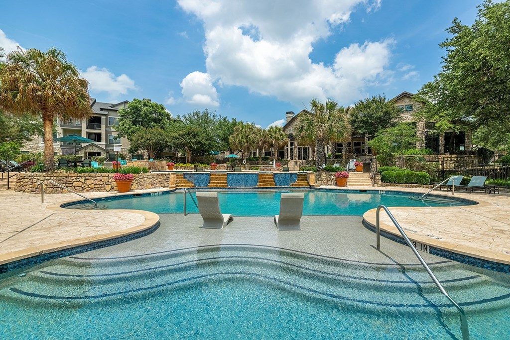 A large swimming pool with a metal railing and steps leading into the water.