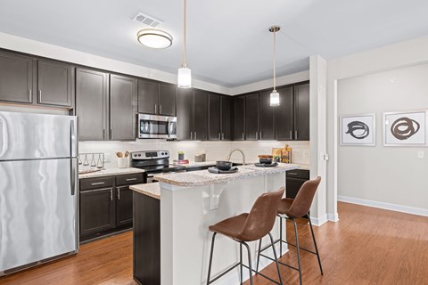 A kitchen with a white refrigerator and black cabinets.