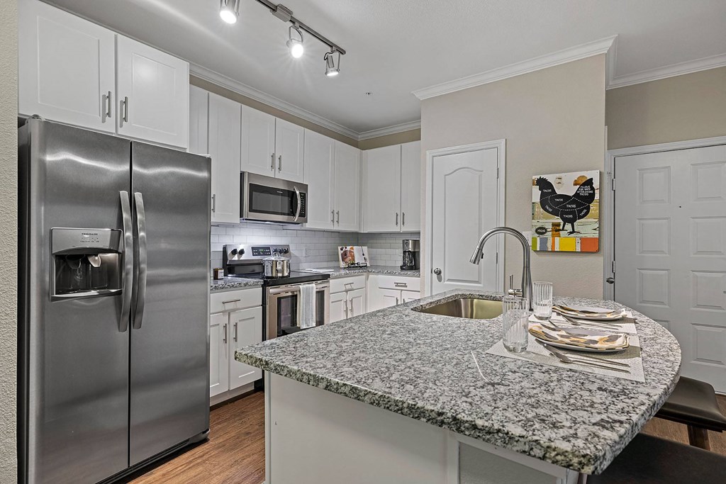 A kitchen with a granite countertop and stainless steel appliances.