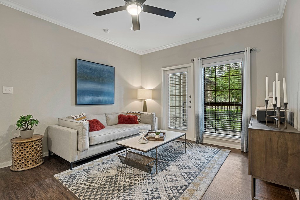 A living room with a white couch, a coffee table, and a ceiling fan.