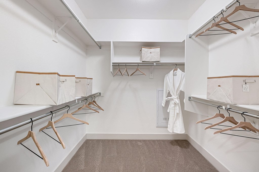 a walk in closet with a rack of clothes and a white robe