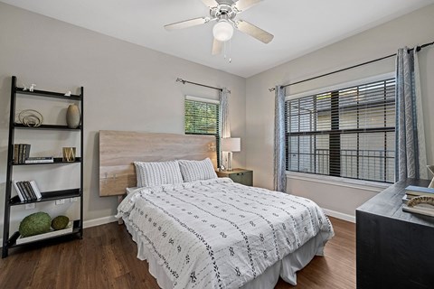 A bedroom with a bed, nightstand, and a ceiling fan.