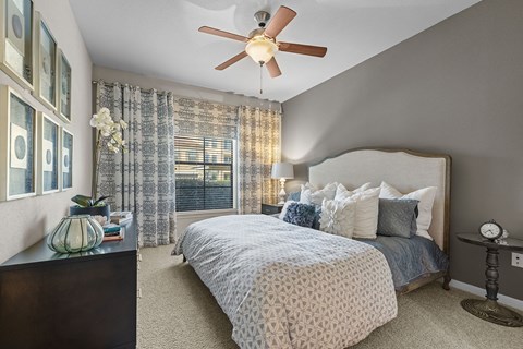 A bedroom with a bed, nightstand, and a ceiling fan.