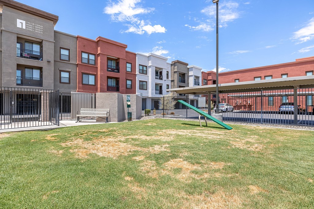 a grassy courtyard with a slide in front of an apartment building