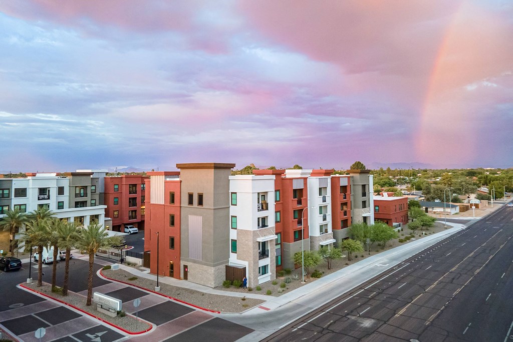 a rainbow in the sky over an apartment complex with palm trees