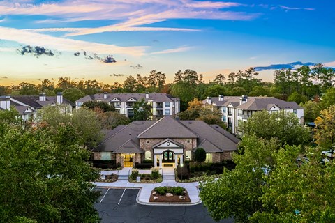 an aerial view of a building with trees and a sunset