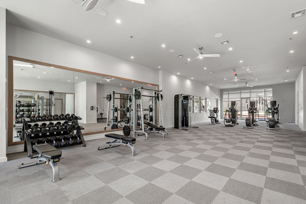 the gym has weights and cardio equipment and a glass wall