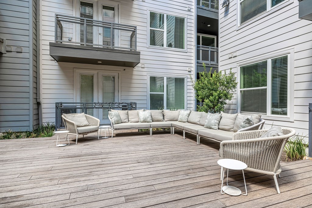 a patio with a couch and chairs in front of a house