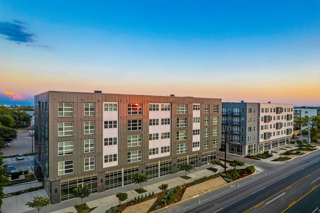 an aerial view of an apartment building with a sunset in the background