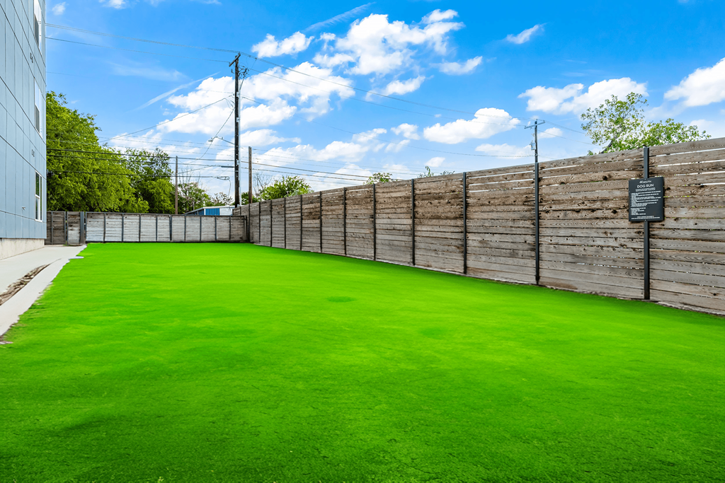 a yard with green grass and a fence with a sign on it