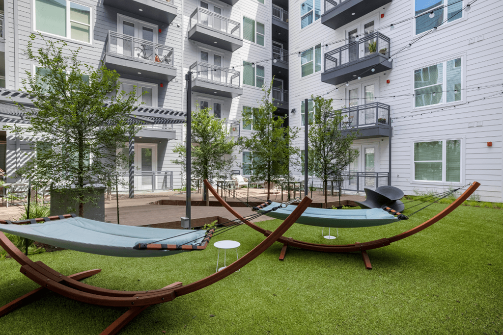 a pair of hammocks in the grass in front of some buildings