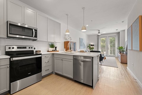 A modern kitchen with stainless steel appliances and wooden floors.