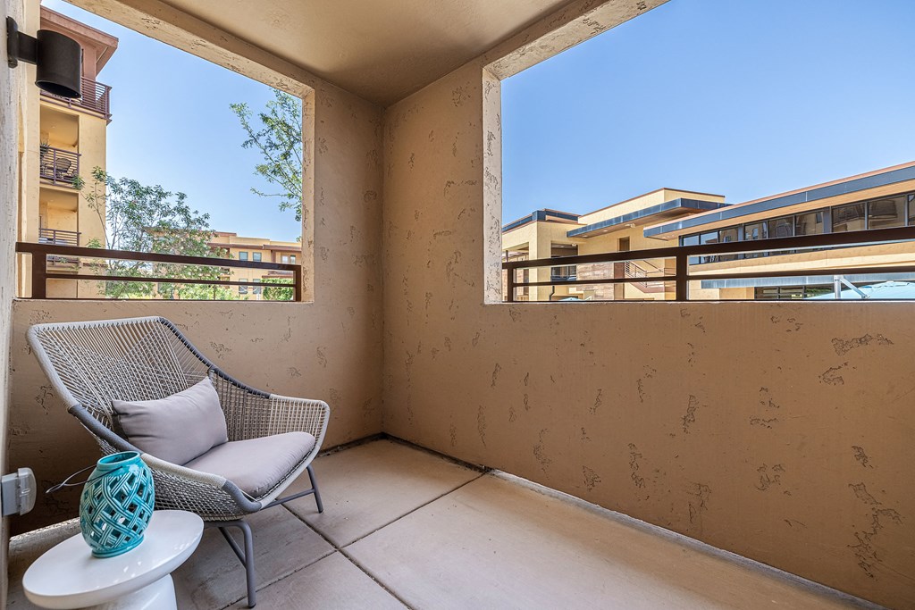 a balcony with a chair and a table and a window