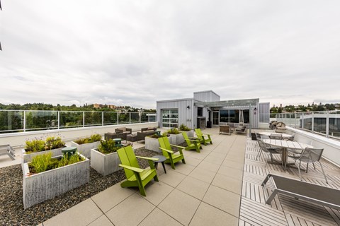 A rooftop patio with green chairs and a building in the background.