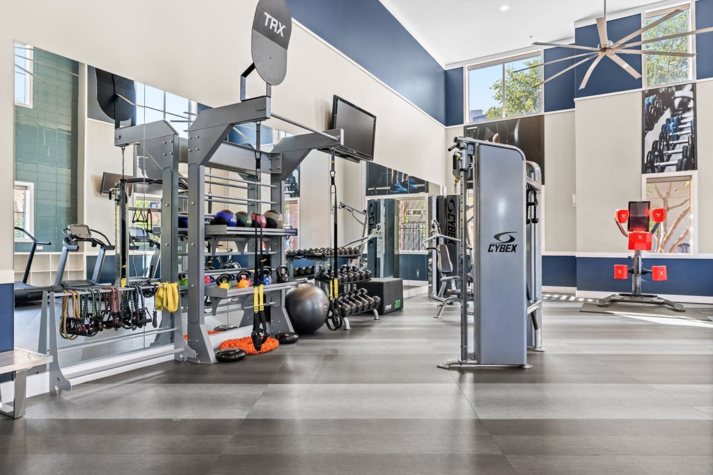 a fitness room with weights and cardio equipment and a wall of windows