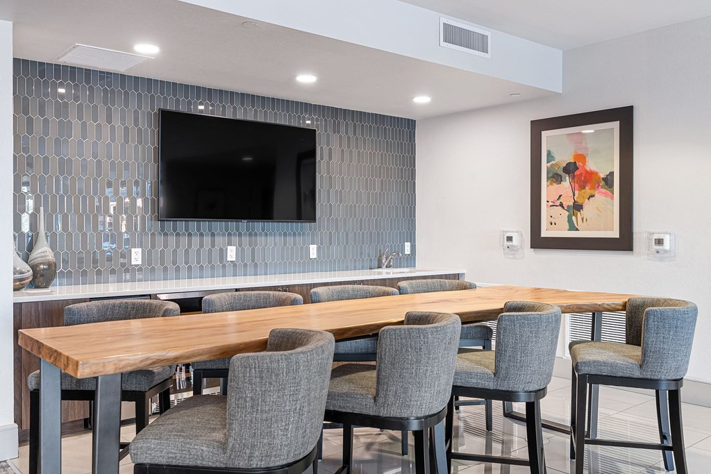 a communal table and chairs in a room with a tv