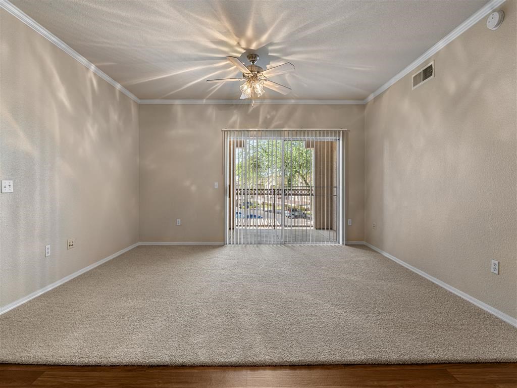 an empty living room with a window and a ceiling fan
