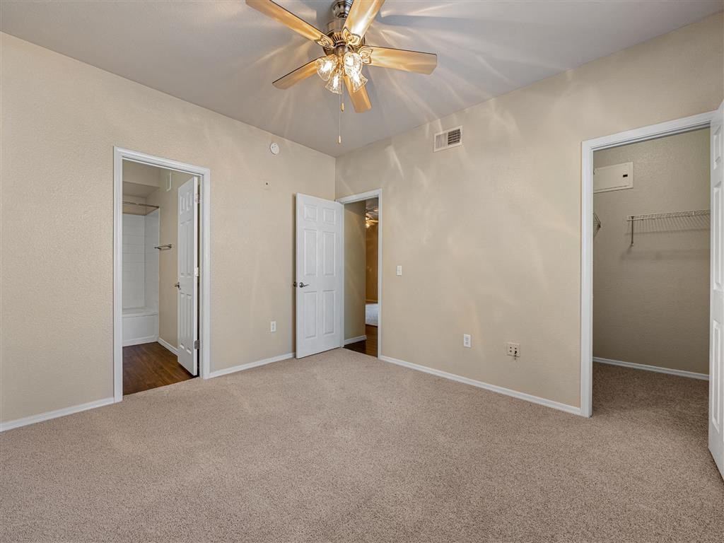 a bedroom with a ceiling fan and a door to a closet