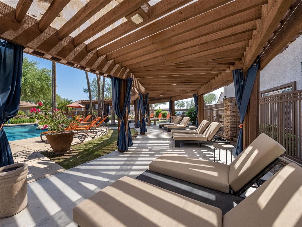 a covered patio with lounge chairs and a pool