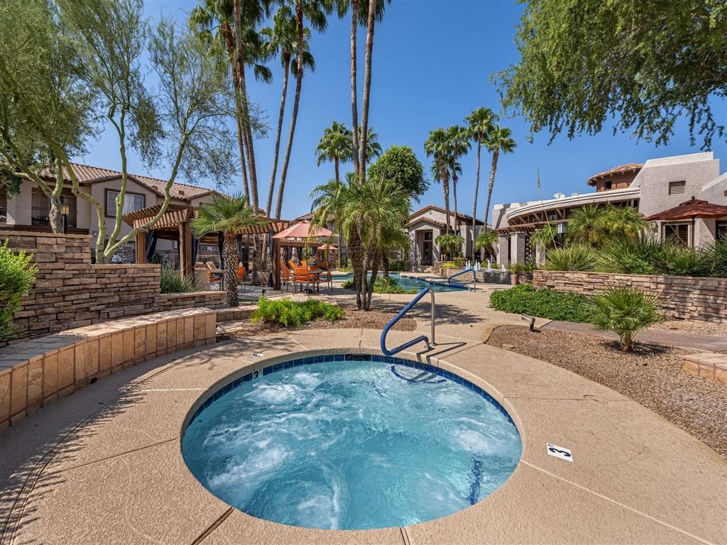a hot tub in a resort style pool with palm trees