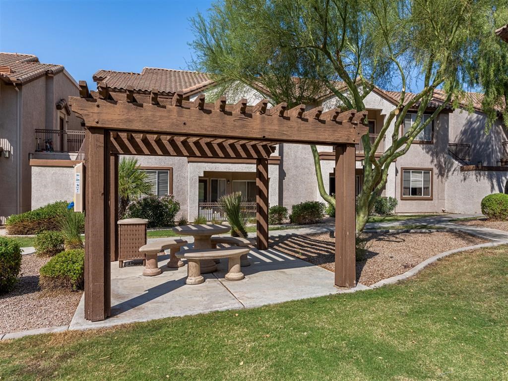a patio with a picnic table and a wooden pergola