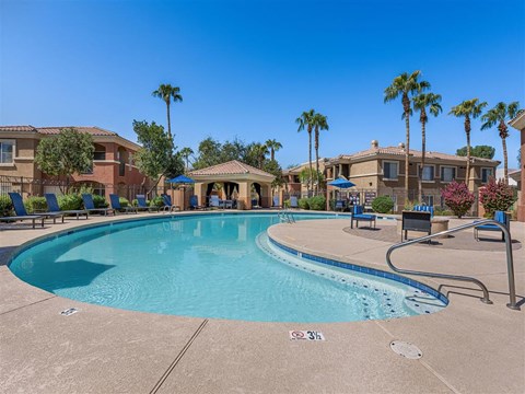 a swimming pool with palm trees and buildings in the background