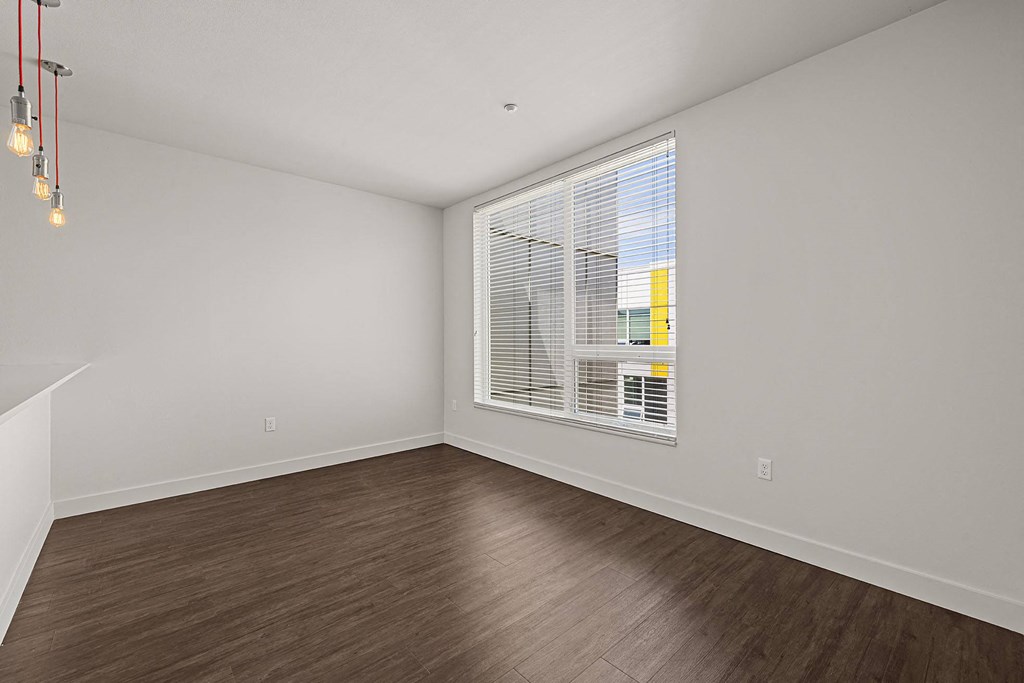 an empty living room with a large window and wood floors