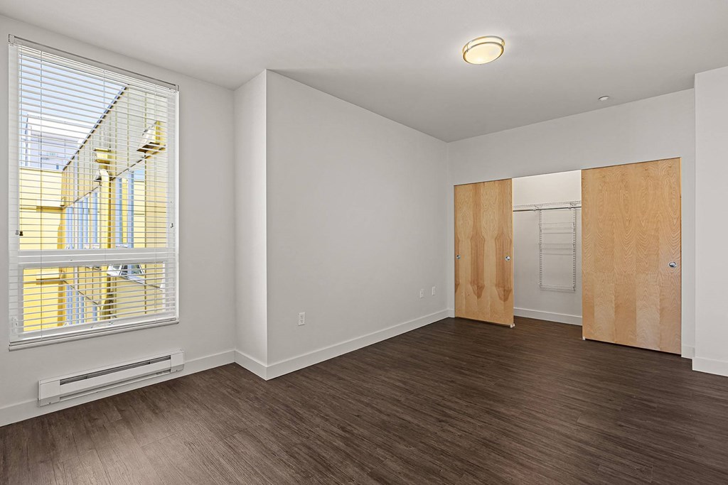 an empty living room with a large window and wood flooring