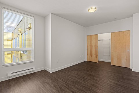 an empty living room with a large window and wood flooring