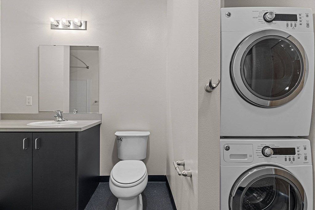 a bathroom with a washer and dryer and a sink and a toilet
