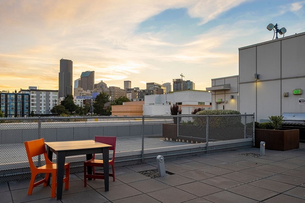a rooftop terrace with a table and chairs and a view of the city