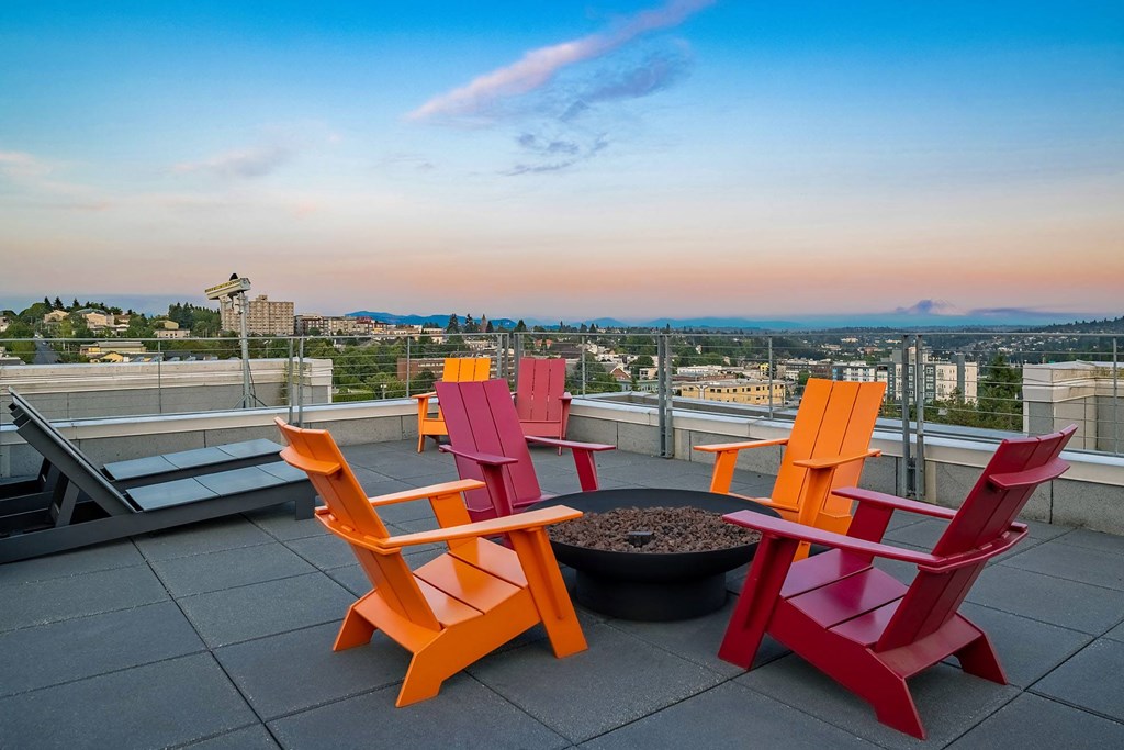 a rooftop patio with orange and red chairs and a fire pit