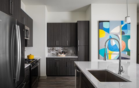 A modern kitchen with a refrigerator, sink, and cabinets.