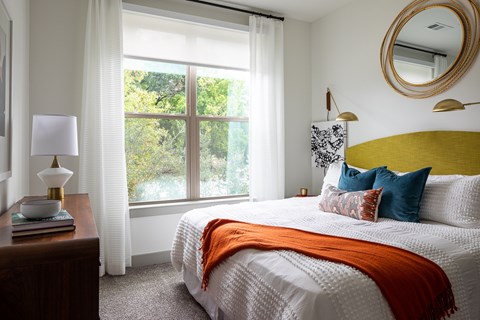 A bedroom with a large bed and a window with curtains.